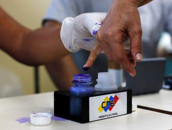 A Venezuelan election official dips into indelible ink the finger of a citizen who just voted in Caracas
